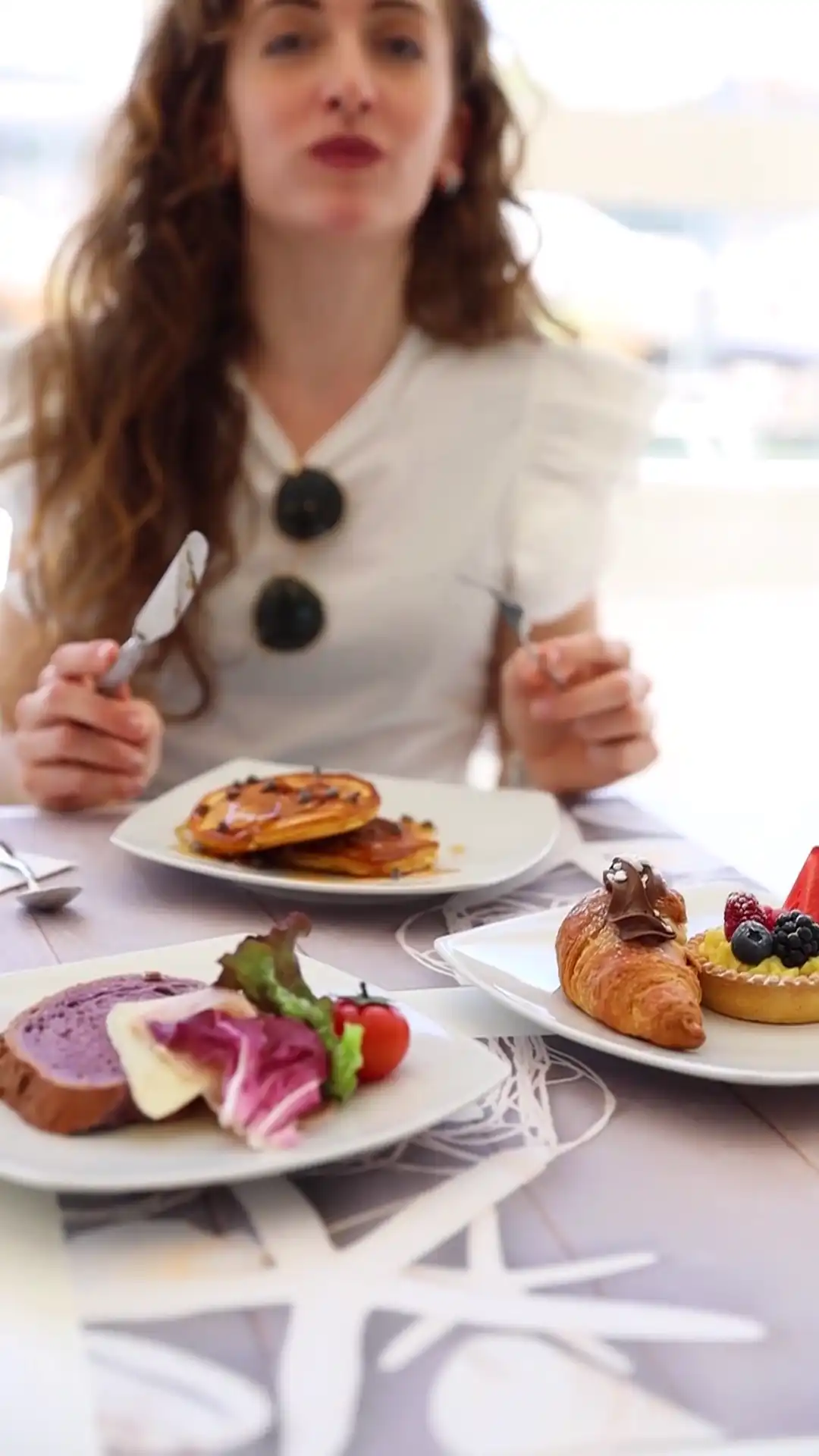Eine Frau sitzt an einem Tisch mit einer Auswahl an Gebäck, Kuchen und Brot.