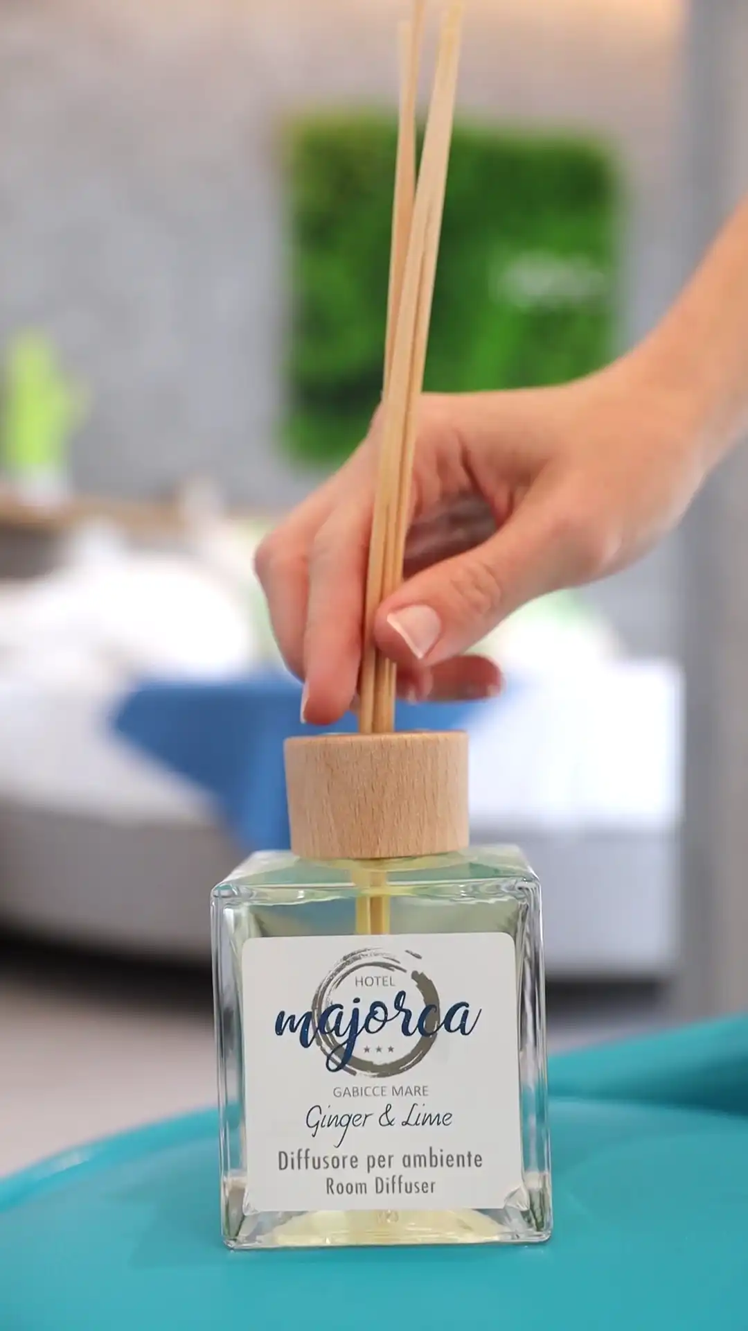 Ein Raumduft-Diffusor mit Stäbchen wird von einer Hand gehalten.